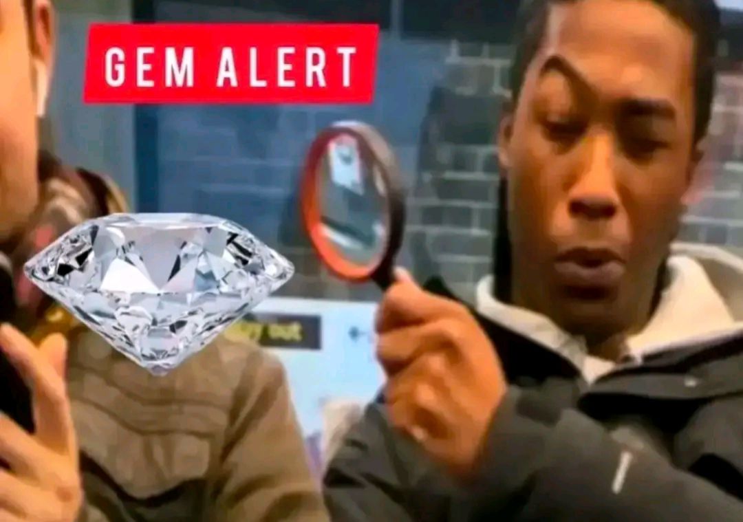 A person with a magnifying glass looking at a gem with the text "GEM ALERT" above it